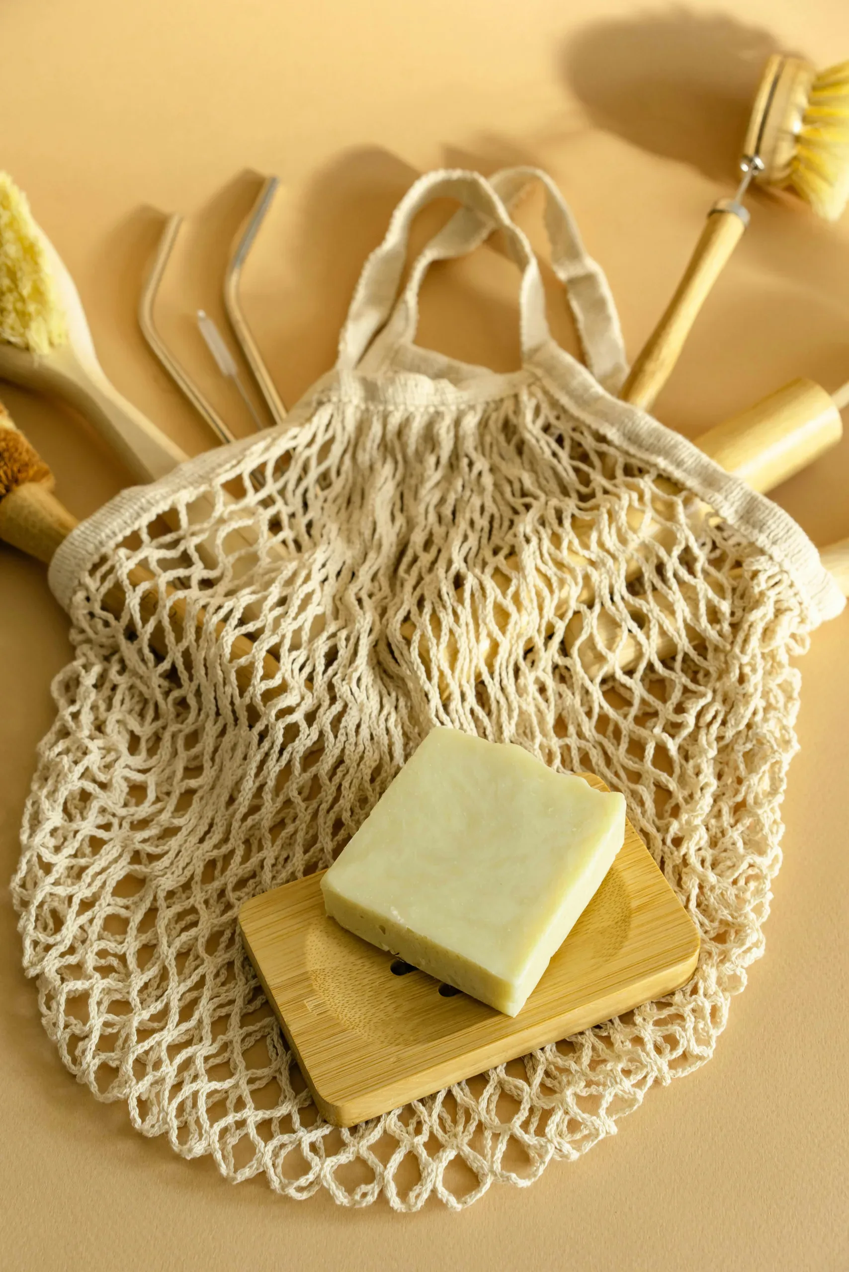 a bar of soap sits atop a mesh bag and bath implements